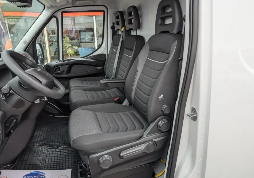 Vue intérieure côté conducteur du fourgon blanc Iveco Daily 35S16 avec sièges tissu gris et tableau de bord noir.