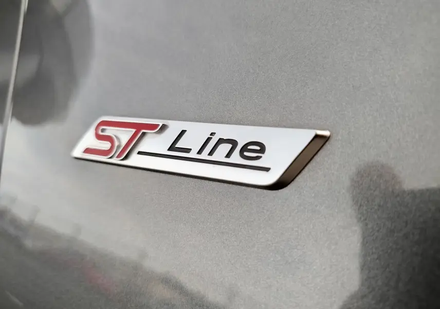 Gros plan sur le logo ST-Line rouge et noir sur la carrosserie gris métallisé d'une Ford Puma 2020.