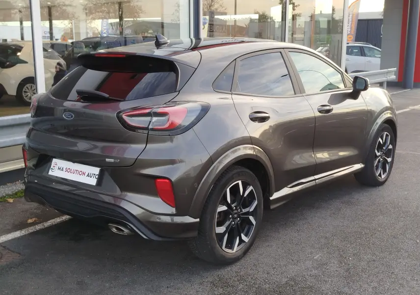 Ford Puma 2020 gris métallisé vu en 3/4 arrière droit, avec jantes alliage noires et vitres teintées.