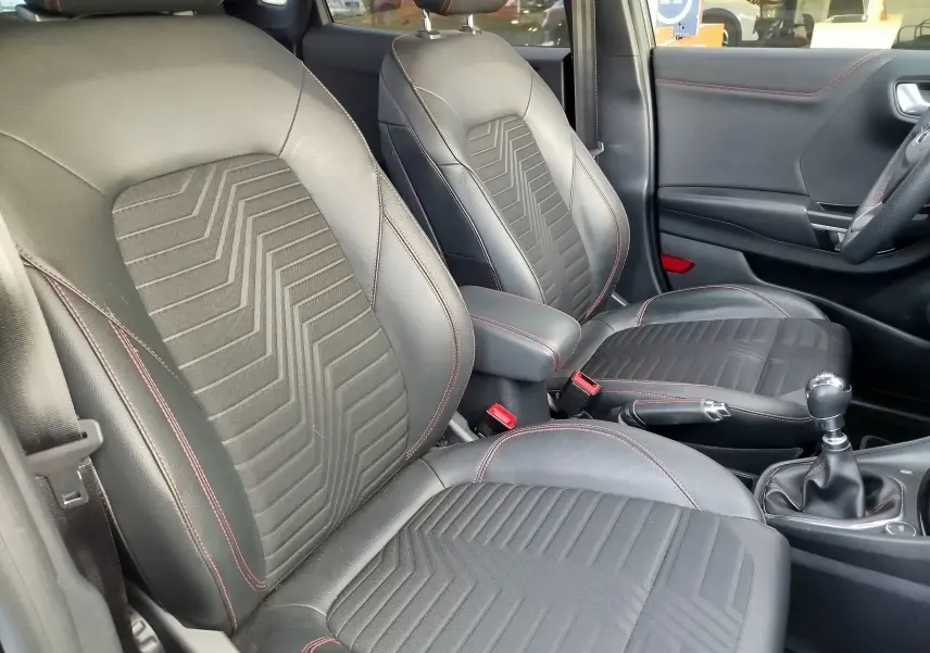 Intérieur avant du Ford Puma 1.0 EcoBoost 2020, sièges noirs avec surpiqûres rouges et levier de vitesse manuel visible.