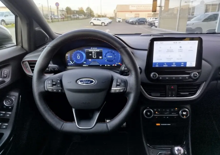 Vue intérieure centrée sur le volant perforé et l'écran tactile du tableau de bord du Ford Puma gris Fashion Métallisé.