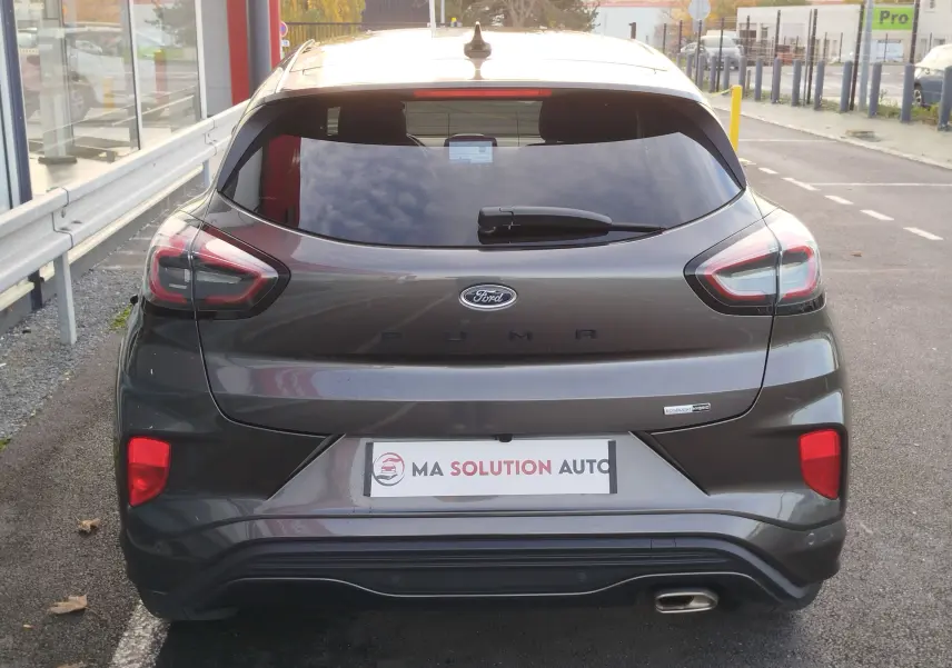 Vue arrière d'une Ford Puma gris métallisé, mettant en valeur ses feux modernes et son badge EcoBoost hybride.