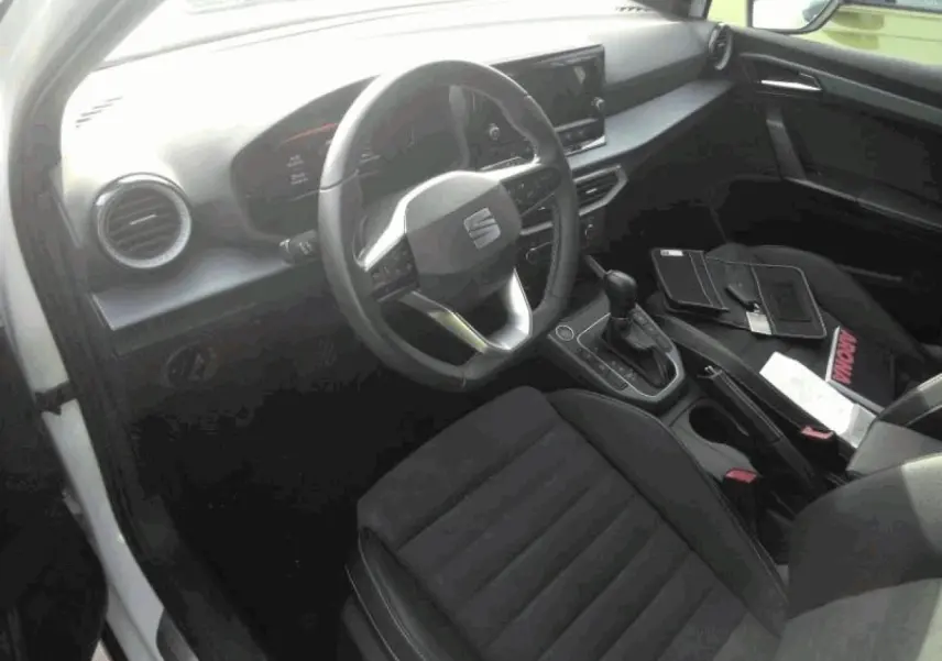 Vue intérieure côté conducteur du SEAT Arona 2025, sellerie suédine noire et tableau de bord moderne avec écran tactile.