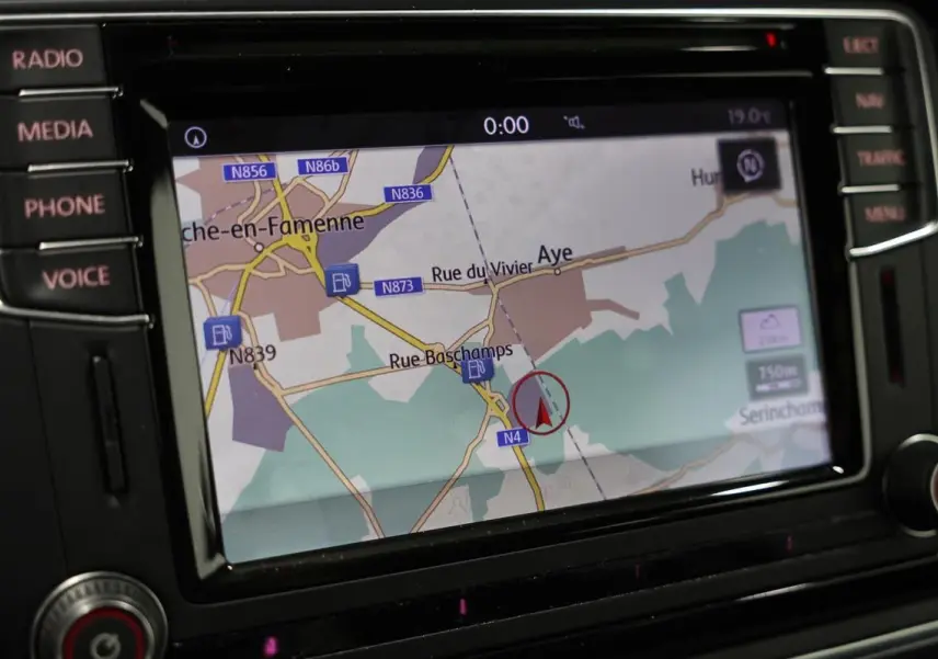 Gros plan sur l’écran GPS intégré au tableau de bord du Volkswagen Coccinelle gris, affichant une carte routière.