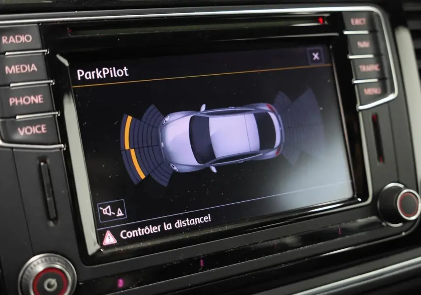 Écran central du tableau de bord montrant l'interface ParkPilot avec la silhouette grise de la Volkswagen Coccinelle en vue de dessus.