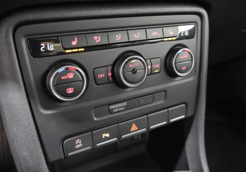 Gros plan sur la console centrale de la Volkswagen Coccinelle 2016, montrant les commandes de climatisation et les boutons de fonction.