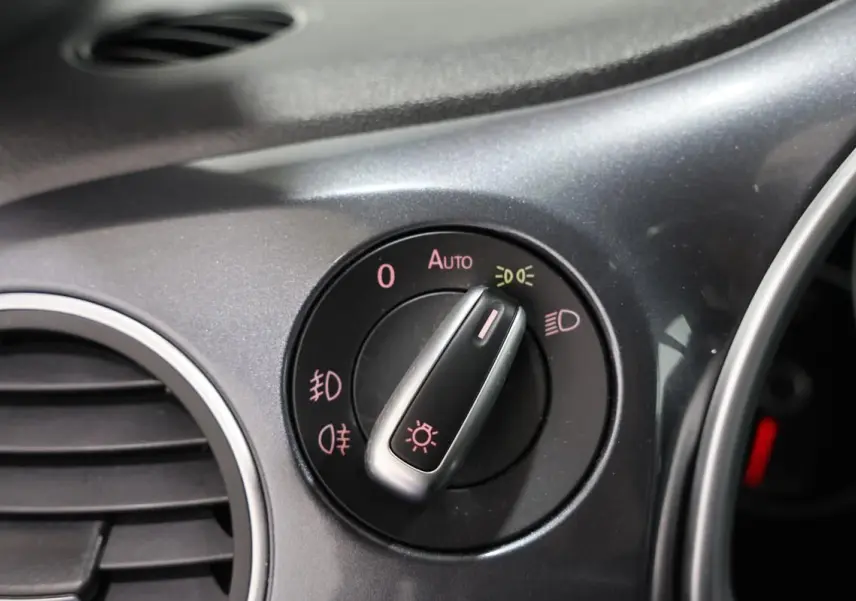 Gros plan sur le bouton de commande des phares du tableau de bord gris de la Volkswagen Coccinelle 2016.