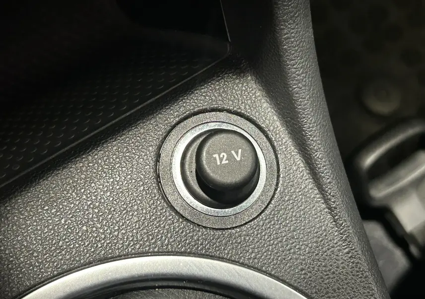 Gros plan sur la prise 12V dans l’habitacle noir de la Volkswagen Coccinelle gris 2016.