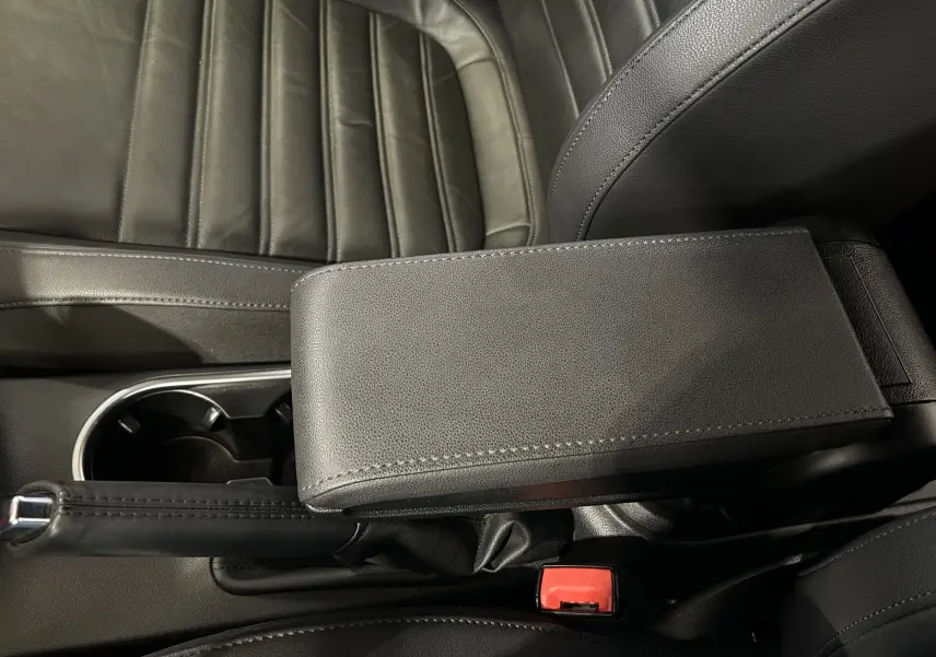 Gros plan intérieur sur l'accoudoir en cuir noir et le frein à main de la Volkswagen Coccinelle 2016.