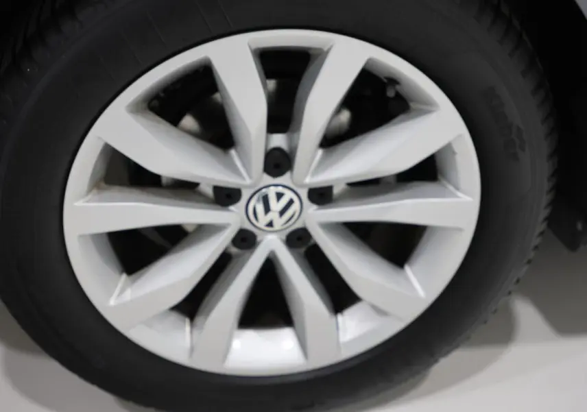 Gros plan sur la jante alliage argentée avec logo Volkswagen au centre d’une Volkswagen Coccinelle gris 2016.