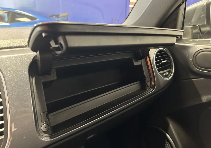 Vue intérieure côté passager du coffre à gants ouvert sur tableau de bord gris d'une Volkswagen Coccinelle 2016.