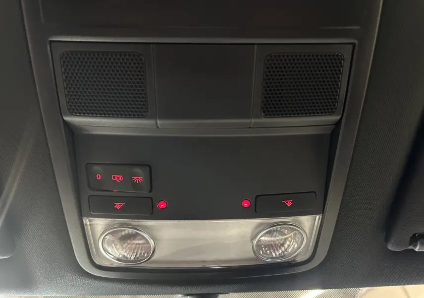Vue en gros plan du plafonnier intérieur gris avec commandes d'éclairage et lampes allumées de la Volkswagen Coccinelle 2016.
