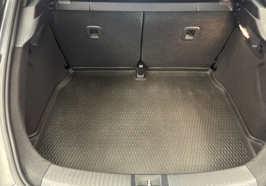 Coffre ouvert vu de l'arrière, tapis de protection noir dans le coffre d'une Volkswagen Coccinelle gris.