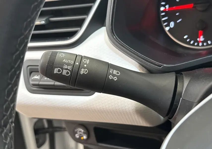 Gros plan sur la commande des phares et clignotants dans l’habitacle blanc de la Renault Clio Evolution TCe 100 GPL 2023.