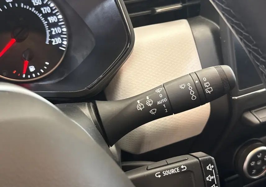 Gros plan sur la manette d’essuie-glace et le compteur de la Renault Clio blanche, vue côté conducteur intérieur.
