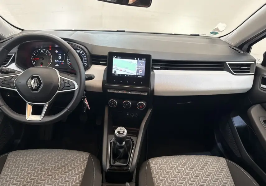 Vue intérieure avant de la Renault Clio blanche 2023, tableau de bord avec écran tactile et volant cuir multifonctions.