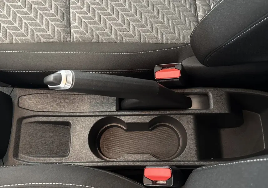 Vue plongeante sur le frein à main et porte-gobelets centraux de la Renault Clio Evolution TCe 100 GPL, intérieur noir.