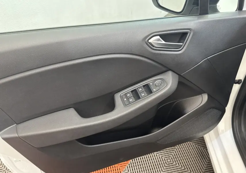 Vue intérieure sur la porte avant gauche noire avec commandes électriques, sur fond extérieur blanc de la Renault Clio Evolution TCe 100 GPL.