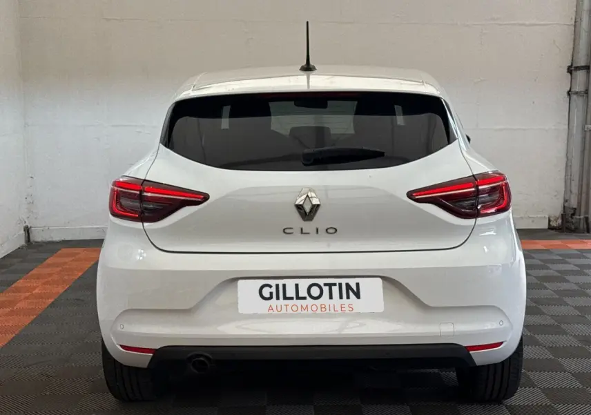 Vue arrière d'une Renault Clio blanche 2023 avec feux LED et logo Renault bien visibles.