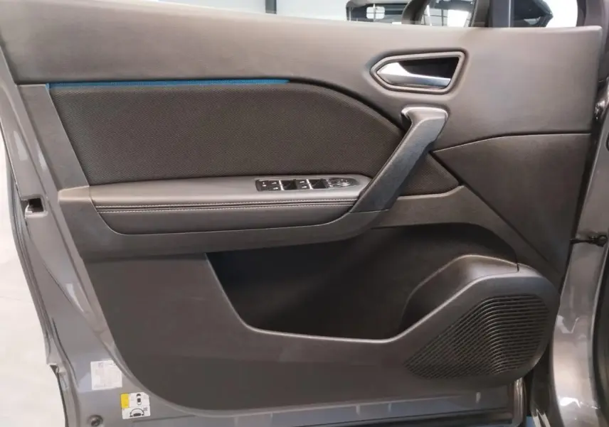 Gros plan sur la porte avant gauche du Renault Symbioz 2025 gris Cassiopée avec commandes de vitres et haut-parleur intégré.