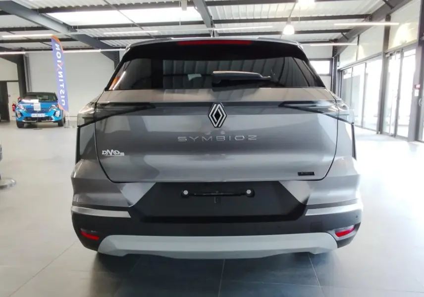 Vue arrière du Renault Symbioz gris Cassiopée avec logo central et feux arrière noirs intégrés, en intérieur showroom.