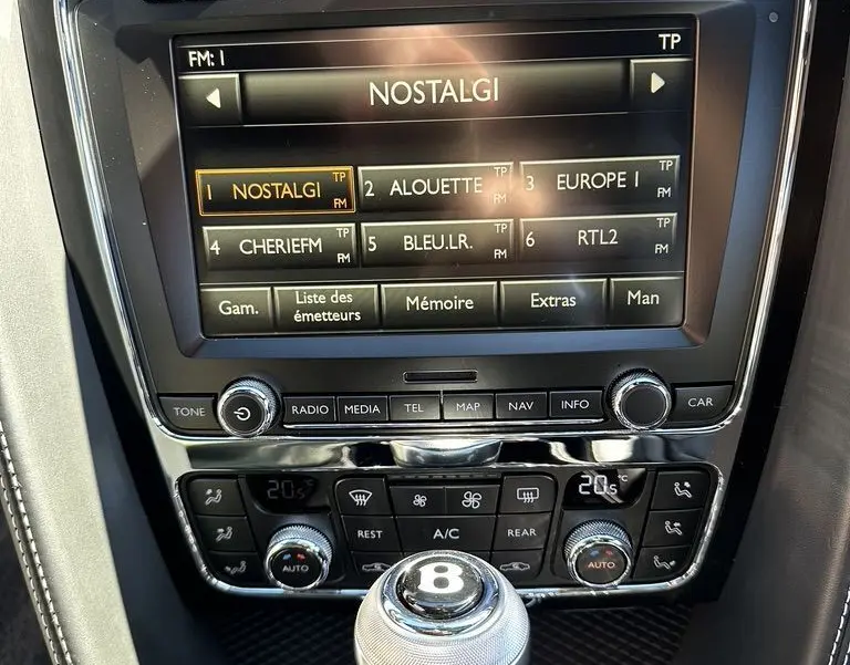 Gros plan sur la console centrale noire de la Bentley Continental GT II avec écran tactile et levier de vitesse marqué du logo Bentley.