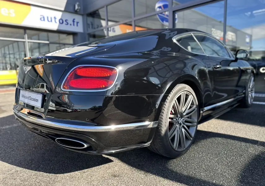 Vue 3/4 arrière droite d'une Bentley Continental GT Speed noire de 2015 avec jantes alliage et feux arrière rouges.