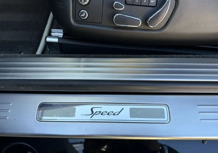 Gros plan sur la plaque de seuil de porte "Speed" et les commandes de siège côté conducteur d'une Bentley Continental GT noire 2015.