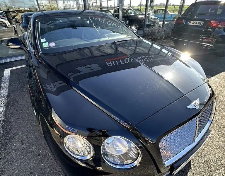 Bentley Continental GT Speed noire vue en 3/4 avant droit, mettant en valeur sa calandre chromée et ses phares ronds.