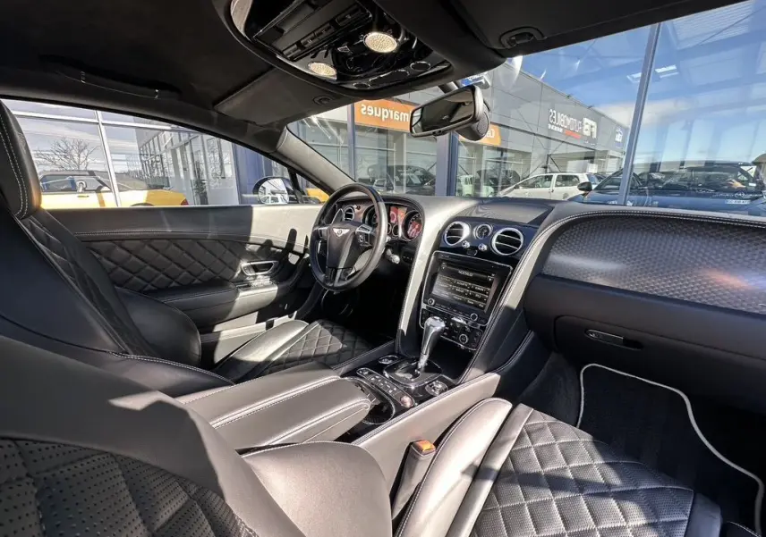 Intérieur noir de la Bentley Continental GT II 2015, vue côté conducteur, cuir matelassé et tableau de bord élégant.