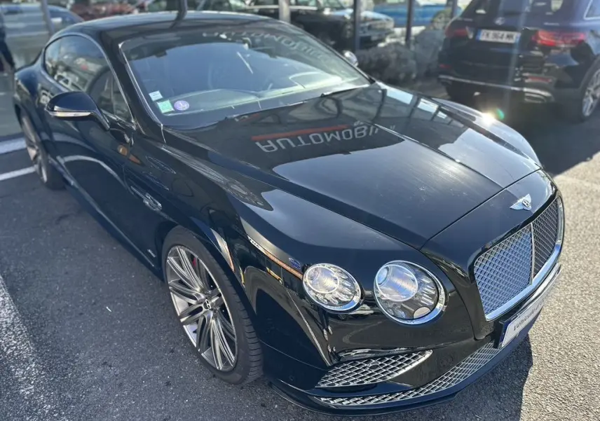 Bentley Continental GT Speed noire vue en 3/4 avant droit, mettant en valeur sa calandre et ses phares ronds distinctifs.