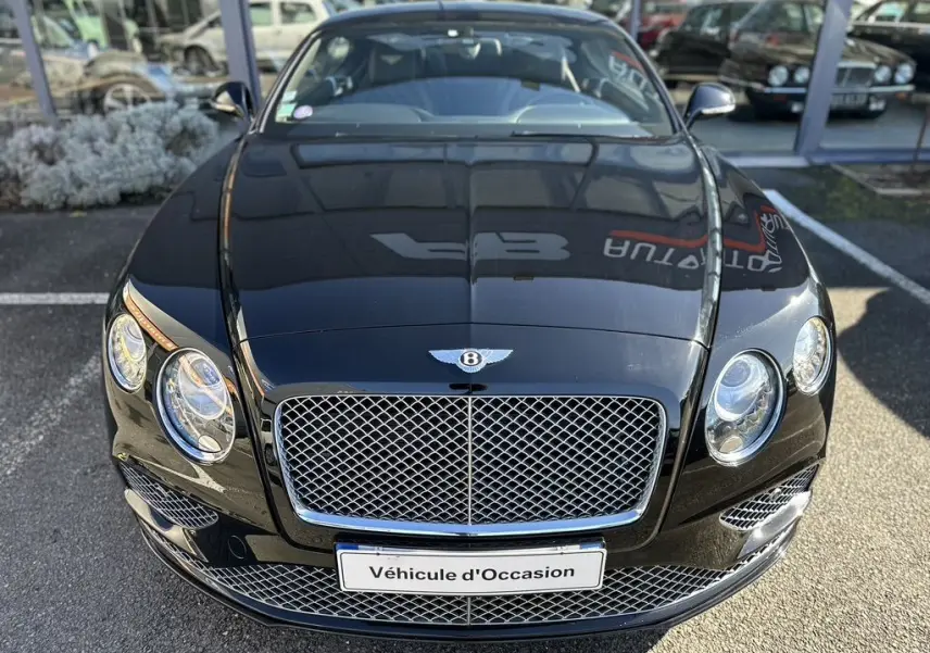 Vue avant rapprochée d'une Bentley Continental GT Speed noire de 2015 avec calandre chromée et phares ronds.