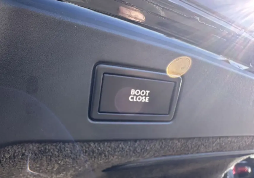 Bouton "Boot Close" en gros plan sur la garniture intérieure du coffre d'une Bentley Continental GT noire 2015.