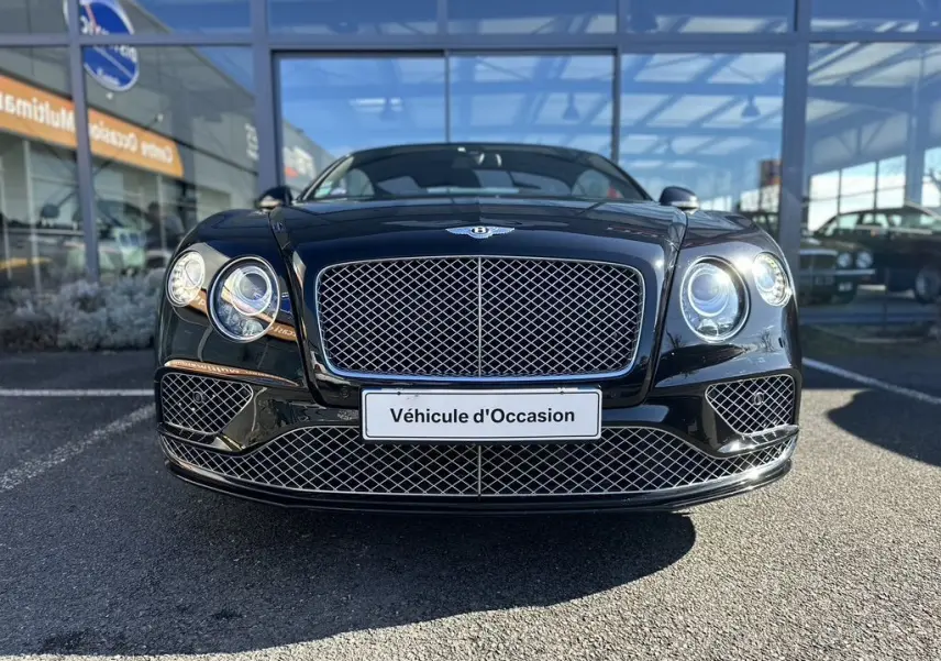 Vue frontale d'une Bentley Continental GT Speed noire 2015 avec calandre en maille chromée et phares ronds allumés.
