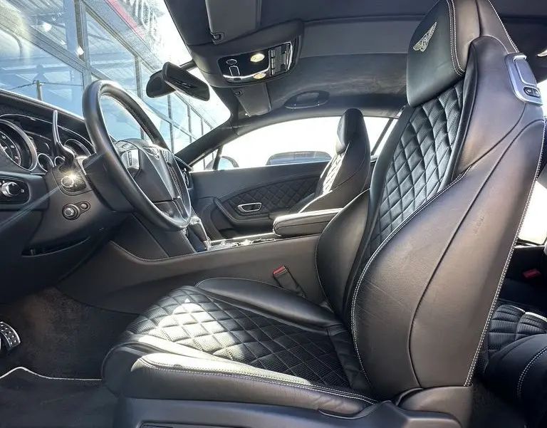 Intérieur noir de la Bentley Continental GT Speed 2015 vu côté conducteur, sièges en cuir matelassé avec logo brodé.
