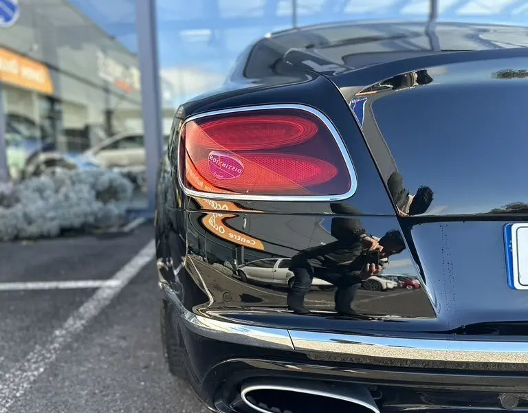 Vue arrière côté gauche d'une Bentley Continental GT Speed noire de 2015 avec feu arrière distinctif et sortie d'échappement ovale chrome.