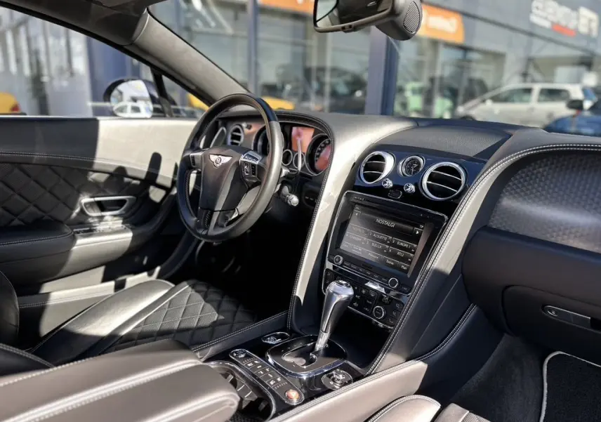 Intérieur cuir noir matelassé de la Bentley Continental GT Speed 2015, vue côté conducteur avec tableau de bord et console centrale.