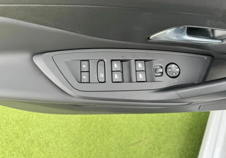 Panneau de commandes des vitres et rétroviseurs côté gauche intérieur d'une Peugeot 308 SW blanche 2024