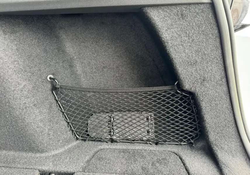 Filet de rangement noir fixé dans le coffre du Peugeot 308 SW blanc Okenite, vue intérieure côté droit.