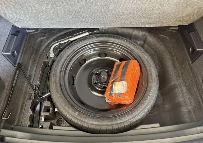 Vue rapprochée du coffre du SEAT Ateca 2023 montrant la roue de secours noire et un kit de sécurité orange.