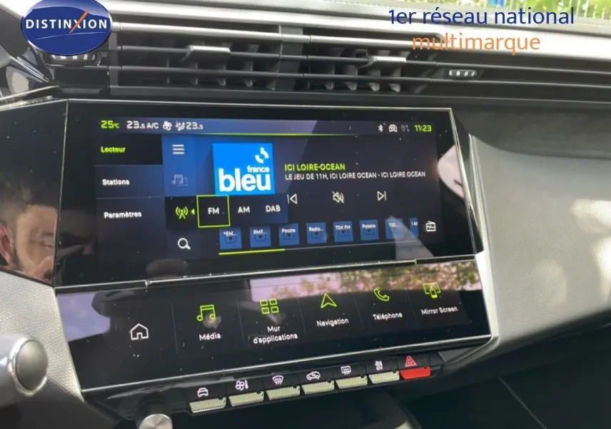 Vue rapprochée de l’écran tactile central du tableau de bord de la Peugeot 308 gris Artense, affichant la radio FM.