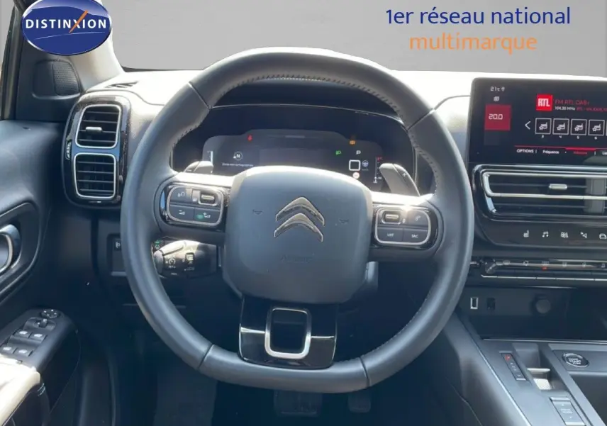 Vue intérieure centrée sur le volant noir du Citroën C5 Aircross 2025 avec tableau de bord digital et écran tactile.