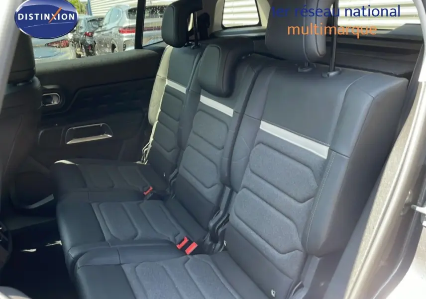 Vue intérieure montrant les sièges arrière en tissu et cuir noir du Citroën C5 Aircross gris platinium 2025, porte ouverte côté droit.