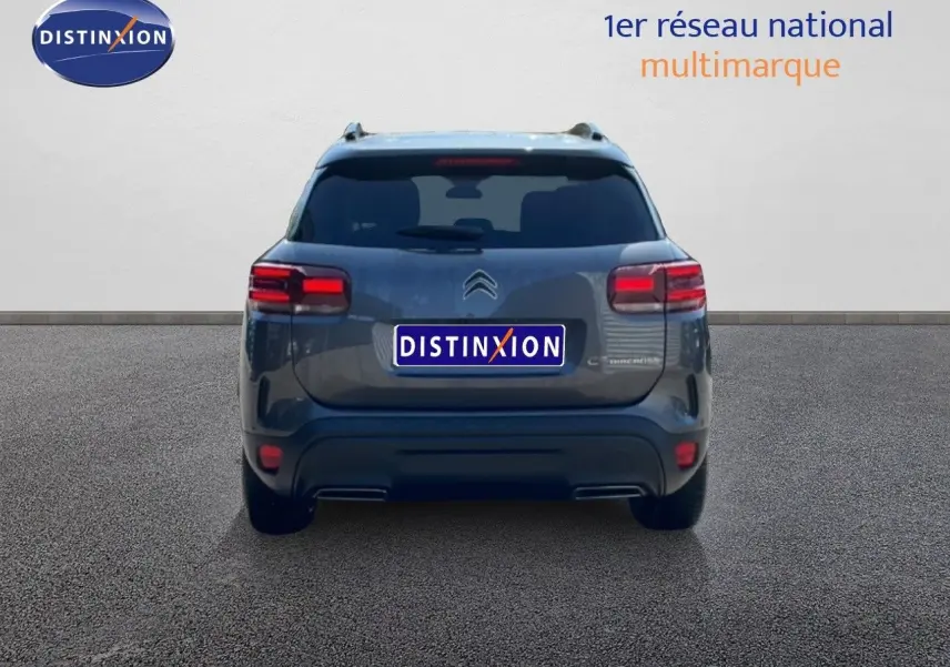 Vue arrière d'un Citroën C5 Aircross gris platinium métal, avec feux arrière allumés sur fond neutre.