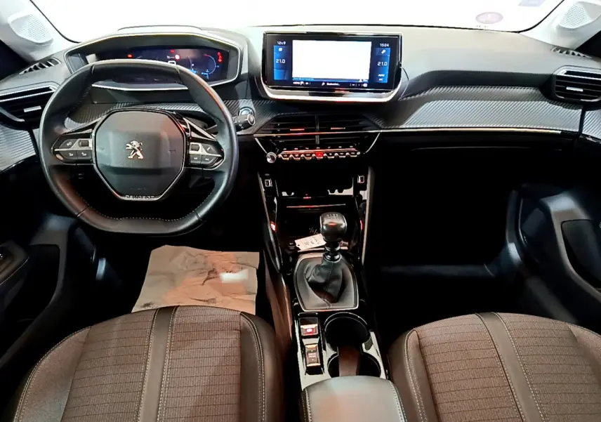 Intérieur de la Peugeot 208 PureTech 100 S&S Allure Business 2020, vue frontale sur tableau de bord et volant cuir noir.