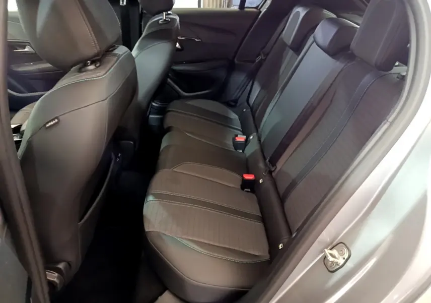 Vue côté droit sur l'intérieur arrière gris foncé de la Peugeot 208 2020 avec sièges en tissu et cuir et ceintures rouges.
