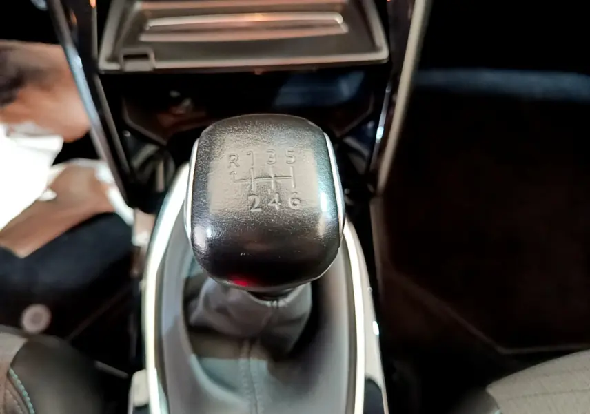 Le levier de vitesses manuel noir de la Peugeot 208 PureTech 100 S&S Allure Business, vue rapprochée intérieure.