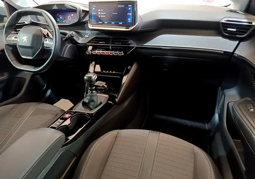 Intérieur de la Peugeot 208 PureTech 100 S&S Allure Business 2020, vue avant côté conducteur, tableau de bord moderne avec écran tactile.