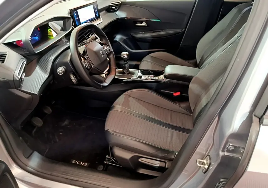 Intérieur côté conducteur d'une Peugeot 208 gris clair, avec tableau de bord numérique et volant cuir multifonctions.