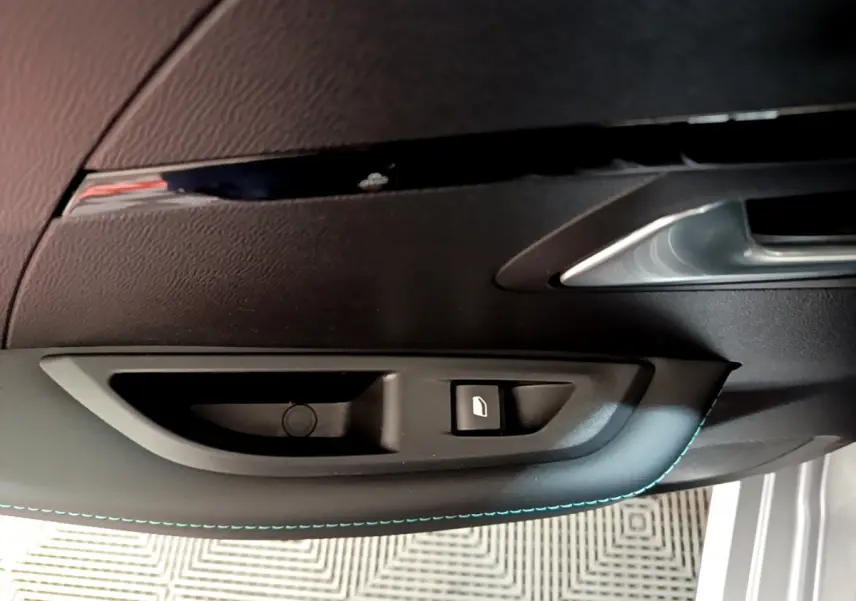 Détail de la poignée intérieure et bouton de verrouillage de la porte côté gauche d'une Peugeot 208 gris clair 2020.